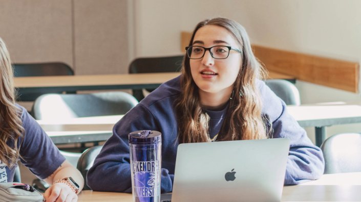 A student in a classroom using a laptop