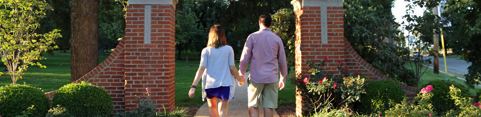 Alumni Holding Hands walking Through the Campus Front Lawn